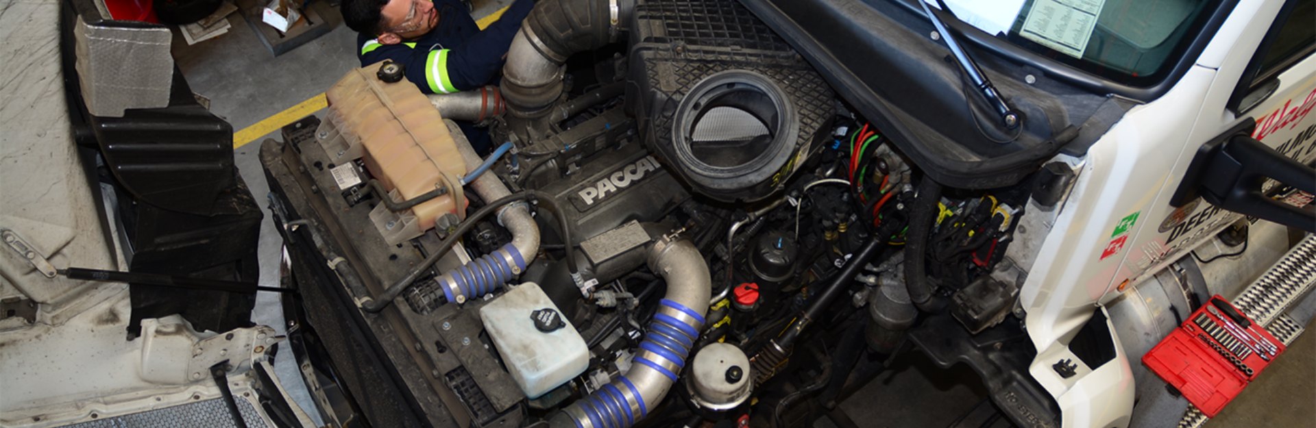 A man working on a PACCAR truck's engine.