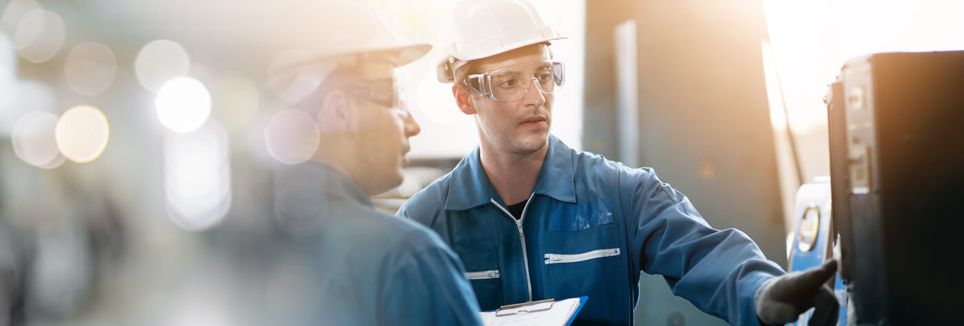Two men looking at a machine while one man presses a button on the machine