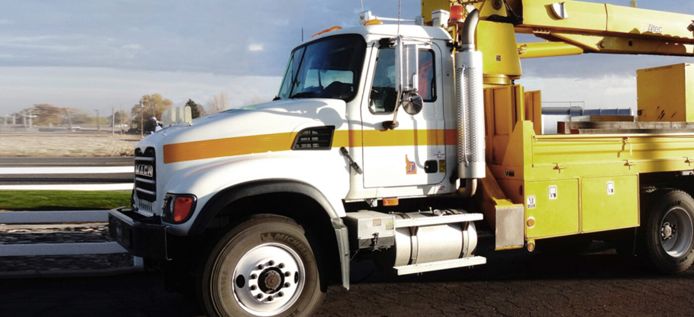A boom mounted truck parked by a field