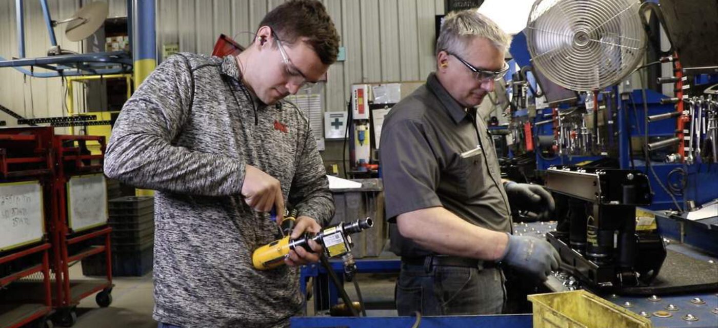 A link intern working on a drill while a man assembles a Cabmate suspension