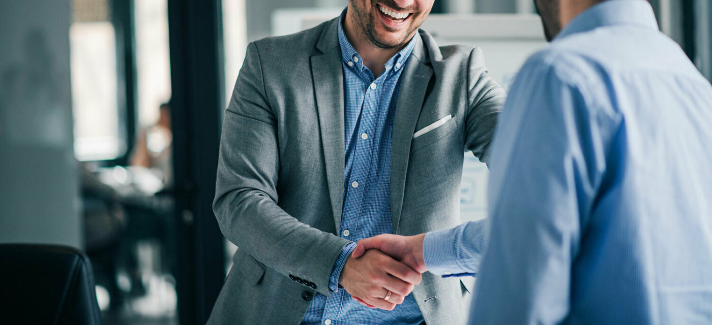 Two men shaking hands both dressed in blue button down shirts