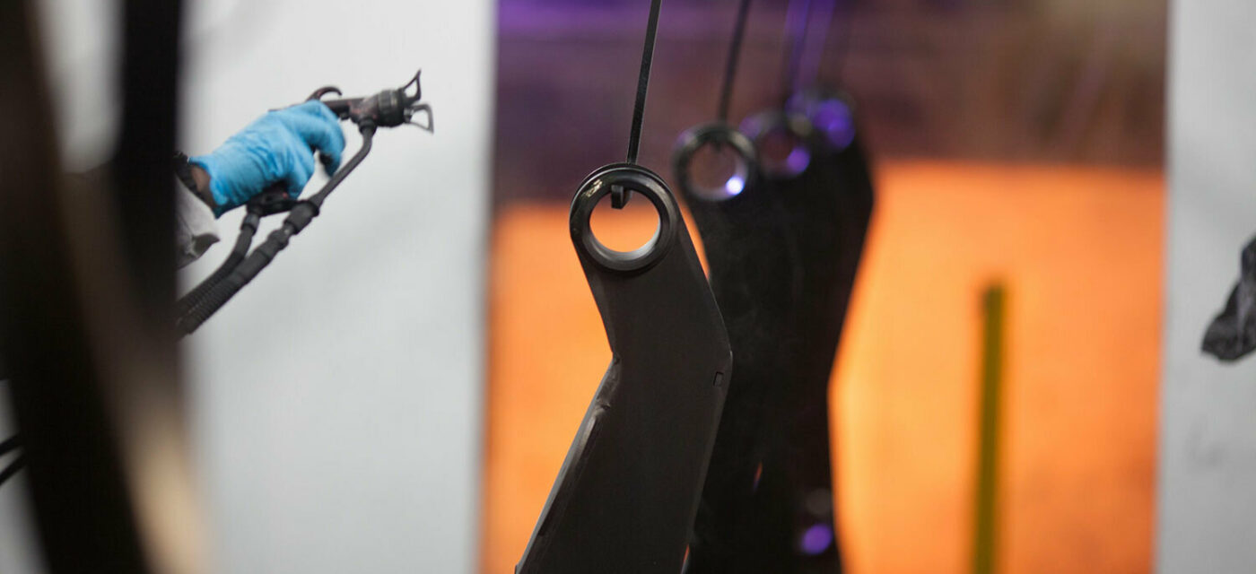 An employee painting Link parts in the paint booth with Link Koat