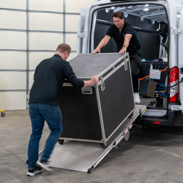 Two men wheeling a large, wheeled equipment container into a cargo van utilizing the Link LSR90 Swivel Ramp