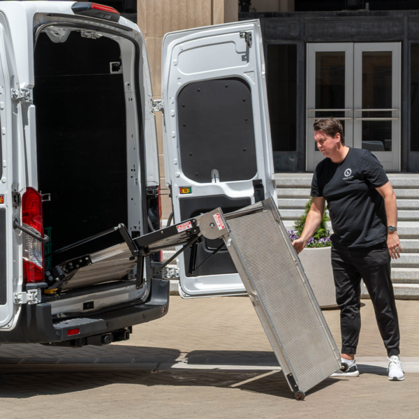 A man utilizing the LSR90 Swivel Ramp's wheel kit and spring assist feature to easily deploy the ramp