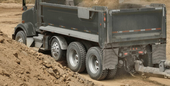 A dump truck with one visible steerable lift axle