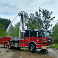 A firetruck with its ladder up spraying water in alternate directions