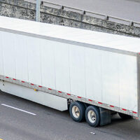 A red truck hauling an enclosed trailer on a highway