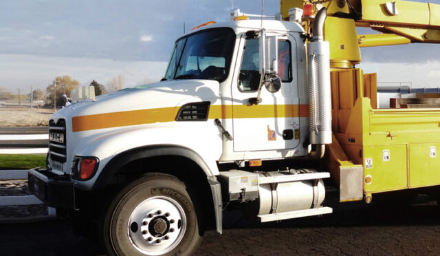 A boom mounted truck parked by a field