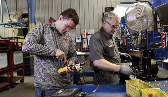A link intern working on a drill while a man assembles a Cabmate suspension