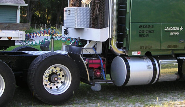 A green semi truck with a flatbed trailer featuring a link 6x2