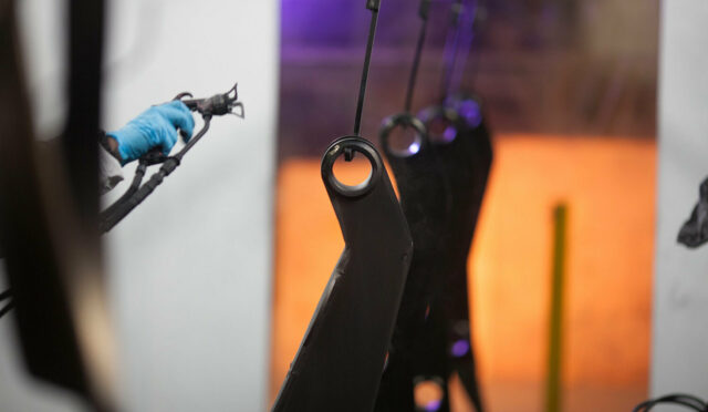 An employee painting Link parts in the paint booth with Link Koat