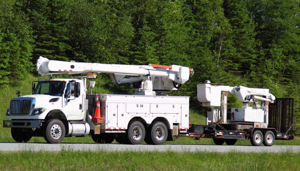 A white bucket truck with trailer.