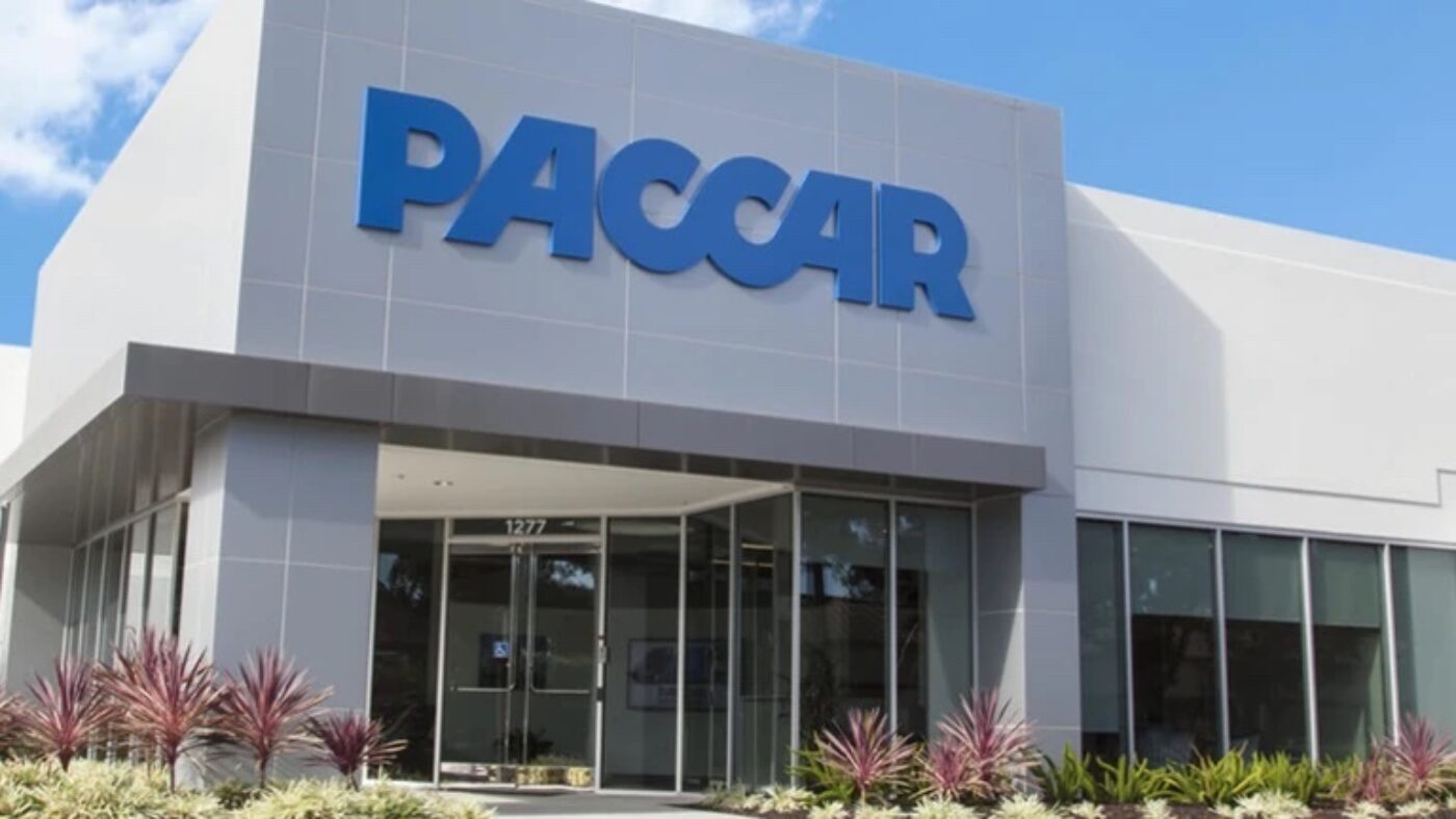 A white building with the word PACCAR in blue over the glass doors