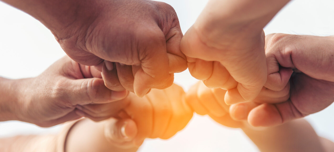 6 people holding fists together in a circle