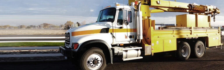 A boom mounted truck parked by a field