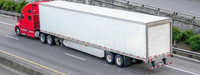 A red truck hauling an enclosed trailer on a highway