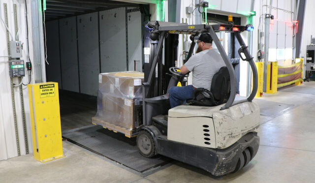 Man using forklift to load pallet into trailer