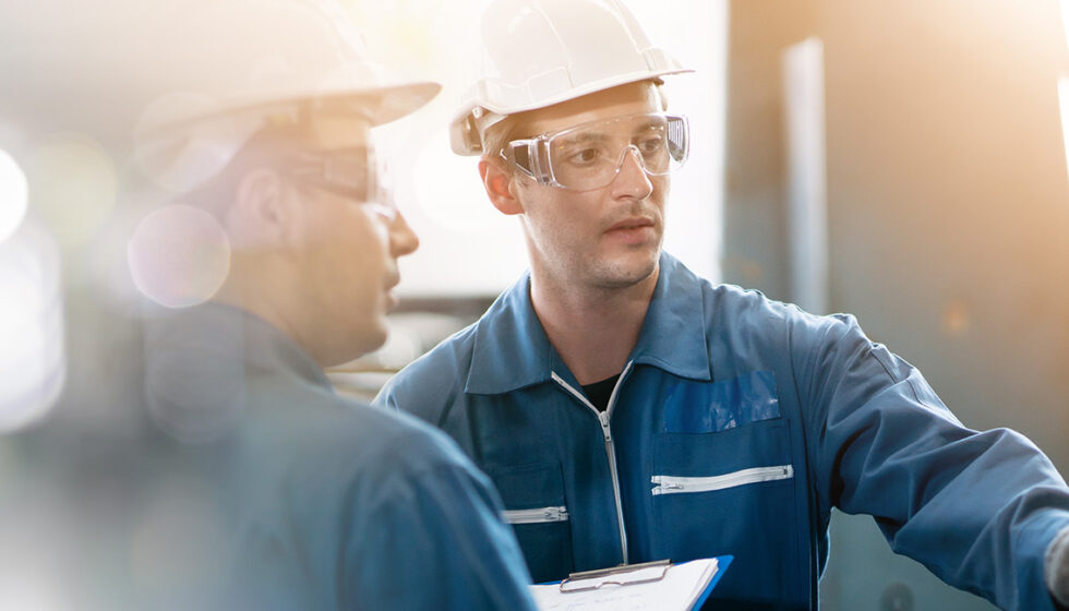 Two men looking at a machine while one man presses a button on the machine
